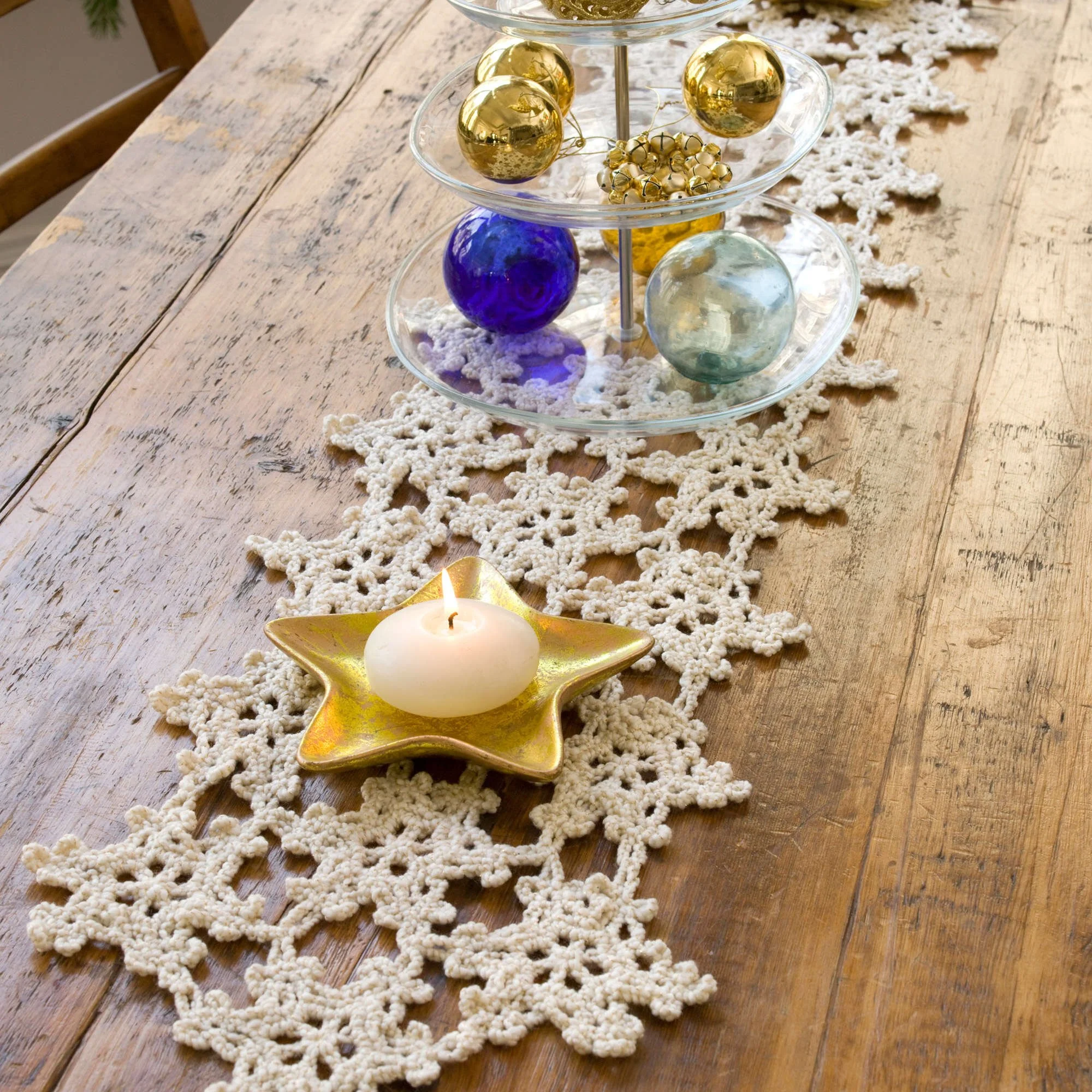 Crochet snowflake table runner pattern displayed on a dining table with festive decor.